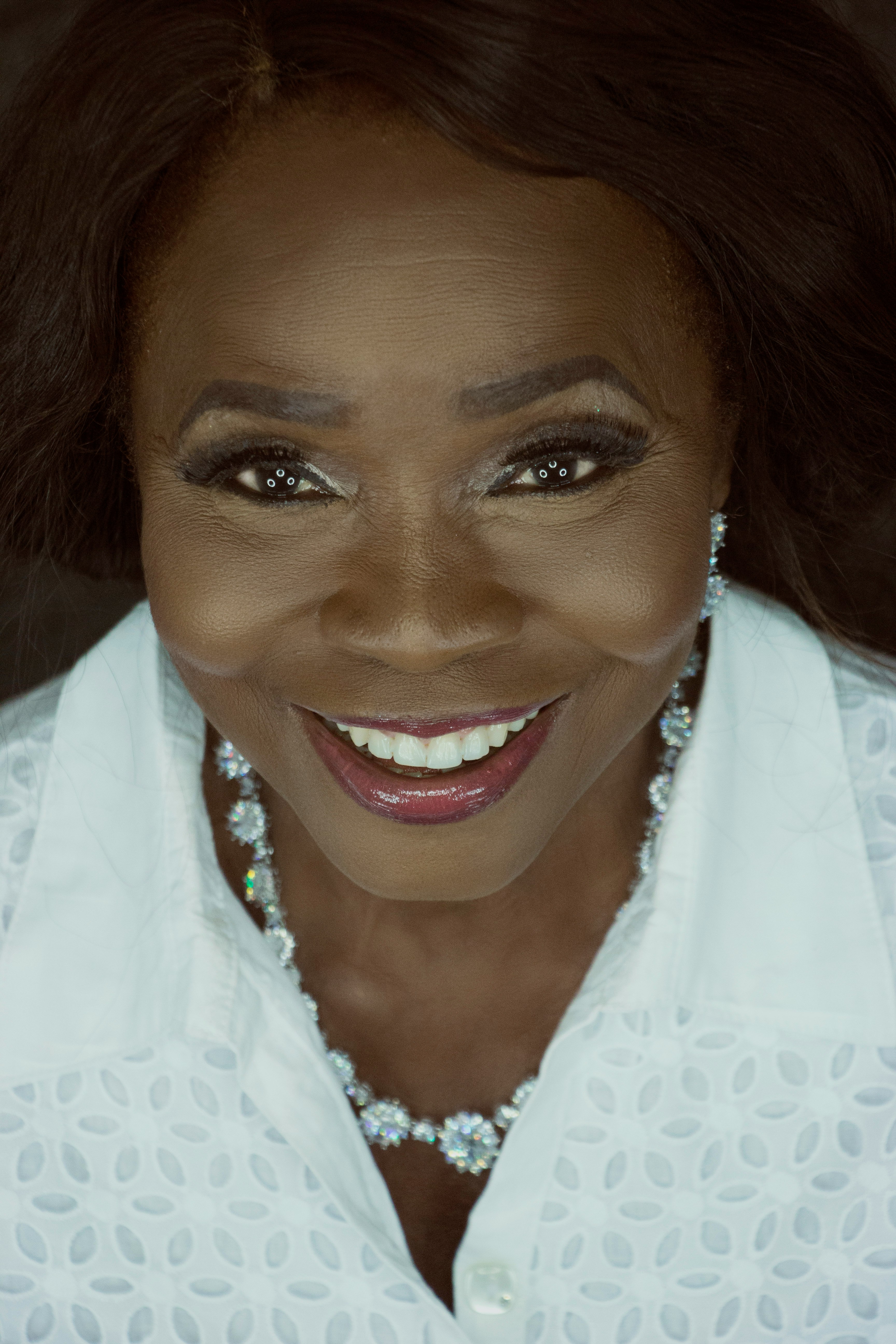 smiling woman wearing red lipstick and white top taking a selfie